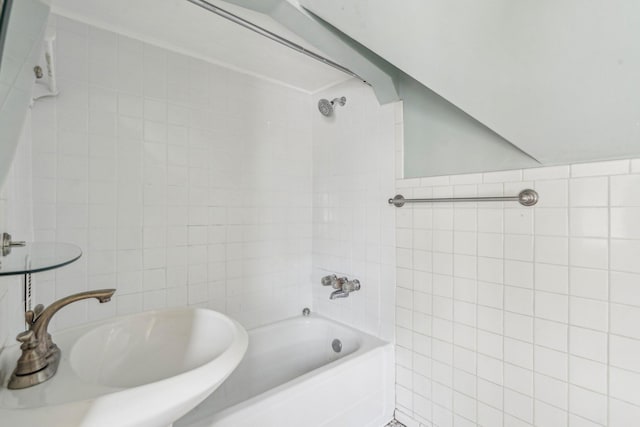 bathroom with a sink, tile walls, and bathtub / shower combination