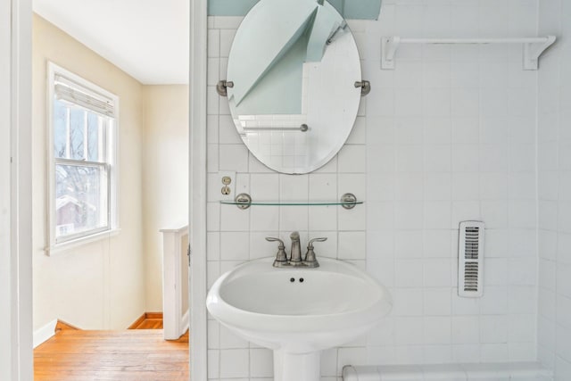 bathroom with wood finished floors, tile walls, and a sink