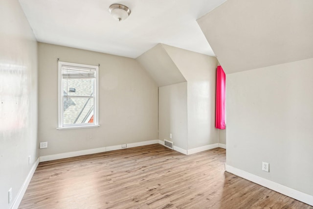 additional living space featuring visible vents, baseboards, lofted ceiling, and wood finished floors