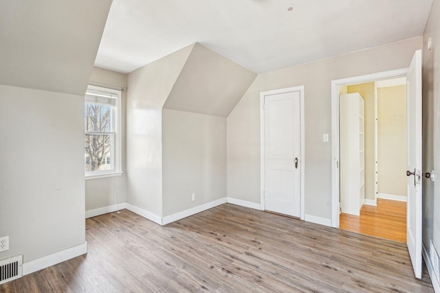 bonus room with visible vents, baseboards, wood finished floors, and vaulted ceiling