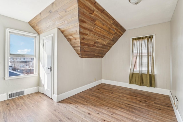 additional living space with lofted ceiling, wood finished floors, visible vents, and baseboards