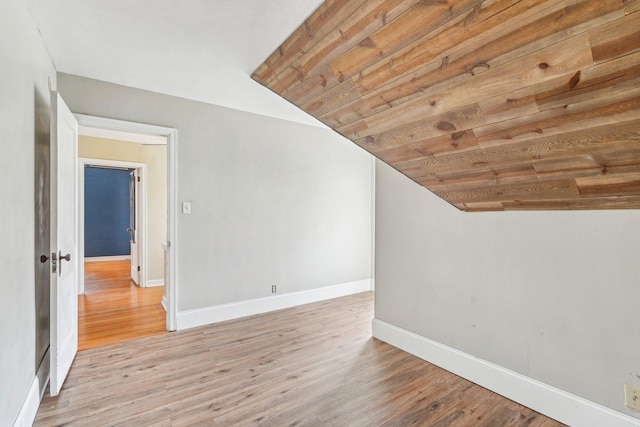 bonus room featuring baseboards, lofted ceiling, and light wood finished floors