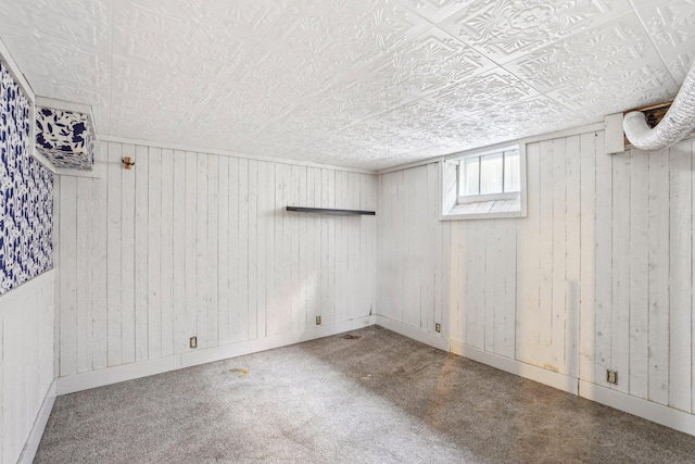 below grade area featuring carpet flooring, baseboards, and wooden walls