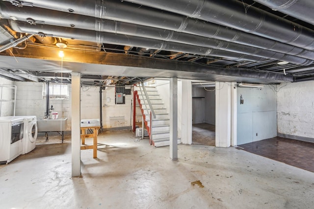 below grade area with stairs, washing machine and clothes dryer, electric panel, and a sink