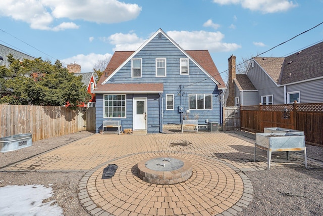 rear view of property featuring a fenced backyard, a chimney, and a patio area