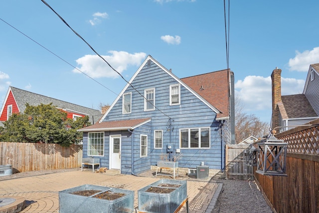 back of property with central air condition unit, a vegetable garden, a gate, and fence