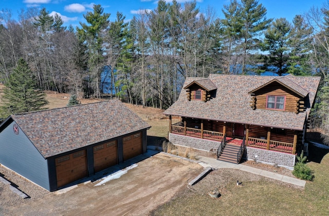 log home featuring stairs, log siding, covered porch, an outdoor structure, and driveway