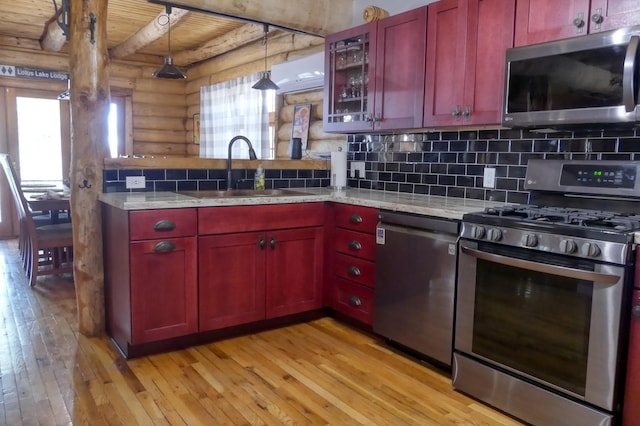 kitchen with decorative backsplash, stainless steel appliances, light wood-style floors, and a sink