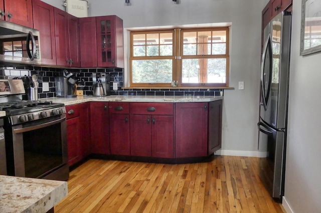 kitchen with tasteful backsplash, dark brown cabinets, appliances with stainless steel finishes, and light wood finished floors