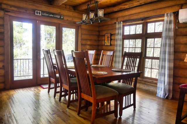 dining area with a wealth of natural light, beam ceiling, log walls, and hardwood / wood-style floors