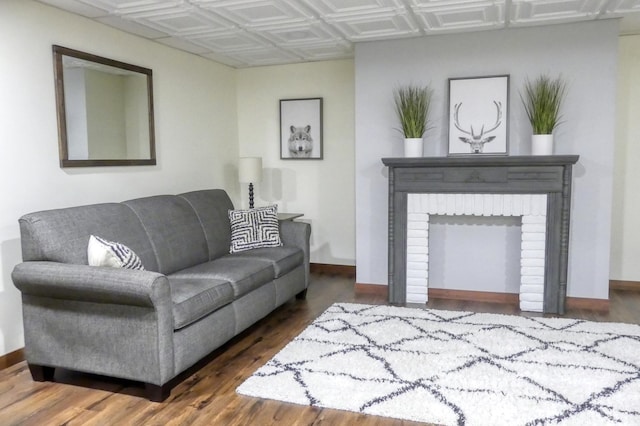 living room featuring wood finished floors, baseboards, and an ornate ceiling