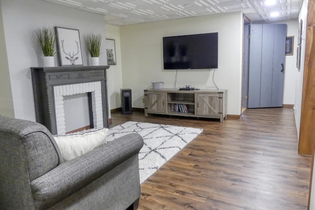 living area featuring an ornate ceiling, baseboards, wood finished floors, and a fireplace