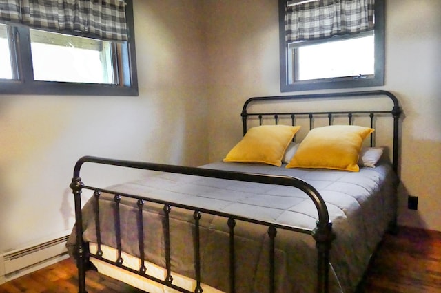 bedroom featuring a baseboard heating unit and wood finished floors