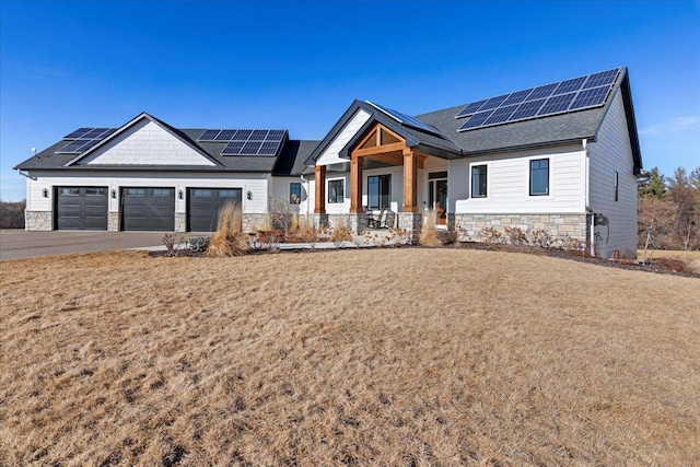 view of front of property featuring a front lawn, a garage, covered porch, and stone siding