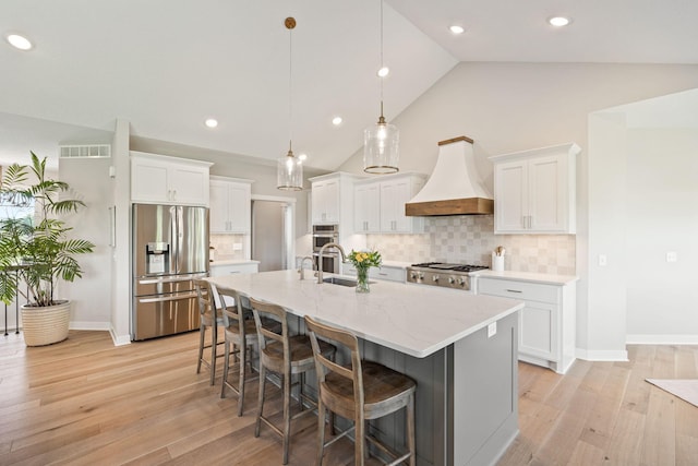 kitchen featuring visible vents, a breakfast bar, stainless steel appliances, white cabinets, and custom exhaust hood