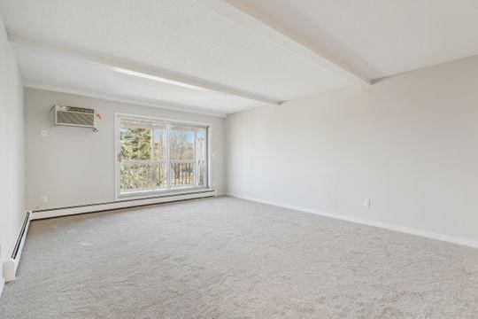 unfurnished room featuring beamed ceiling, carpet, baseboards, and baseboard heating