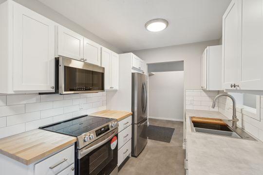 kitchen with decorative backsplash, appliances with stainless steel finishes, white cabinetry, and a sink