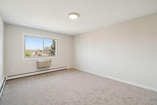 empty room with carpet floors, baseboard heating, baseboards, and a baseboard radiator