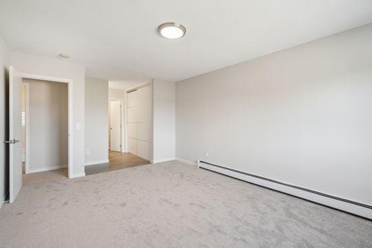 carpeted spare room featuring a baseboard radiator and baseboards