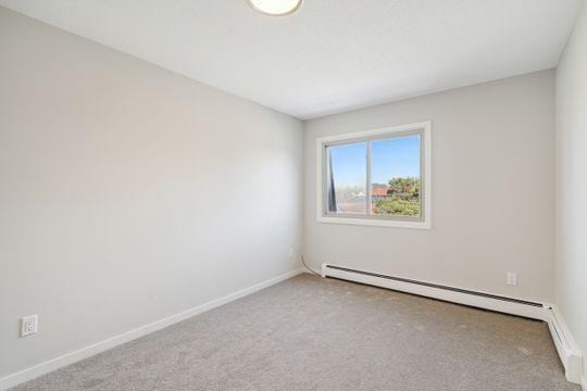 carpeted spare room with baseboards and a baseboard radiator