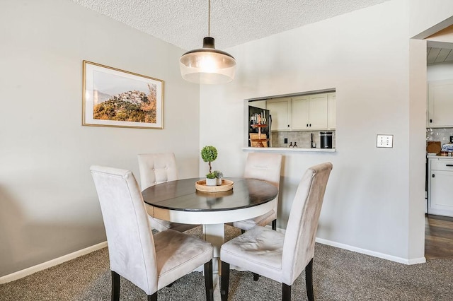 dining area featuring a textured ceiling, baseboards, and dark colored carpet