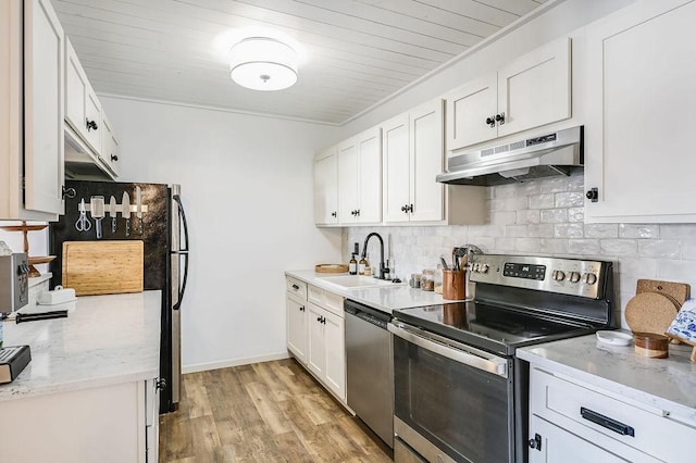 kitchen featuring tasteful backsplash, under cabinet range hood, stainless steel appliances, white cabinetry, and a sink