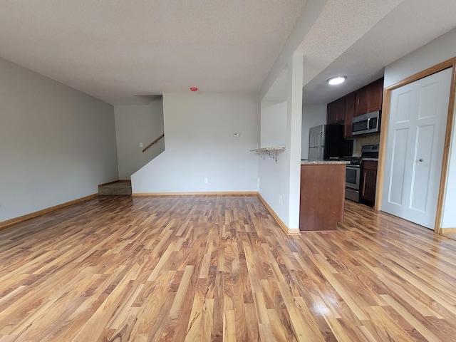 kitchen with baseboards, open floor plan, stainless steel appliances, and light wood-style floors