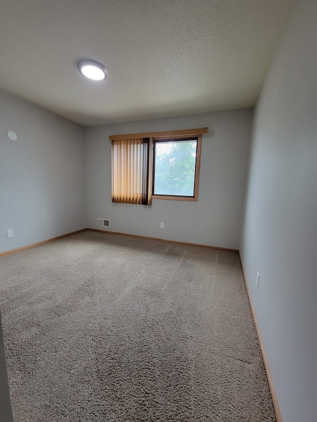 unfurnished room with baseboards, visible vents, carpet floors, and a textured ceiling