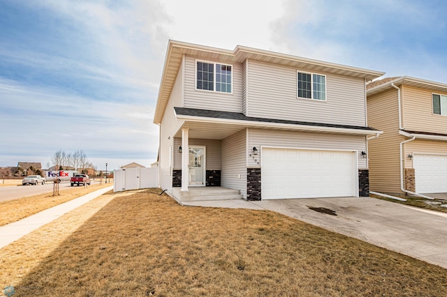 multi unit property featuring stone siding, driveway, an attached garage, and a front yard