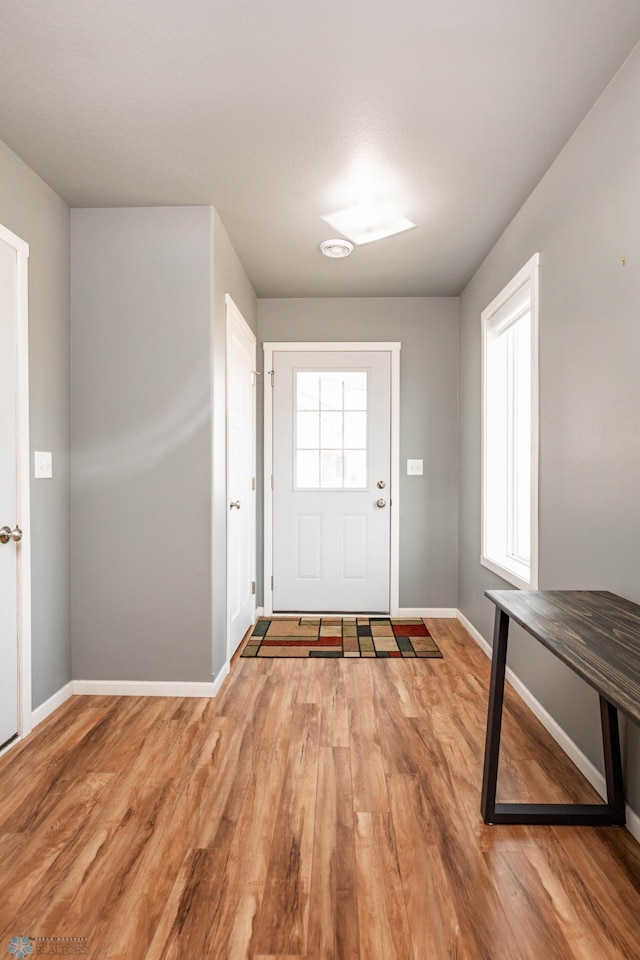 entryway with baseboards, a healthy amount of sunlight, and light wood finished floors