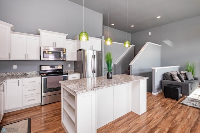 kitchen with open shelves, a kitchen island, stainless steel appliances, white cabinets, and light wood finished floors