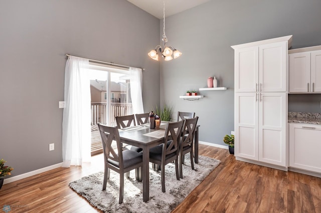 dining area with light wood finished floors, baseboards, a high ceiling, and an inviting chandelier