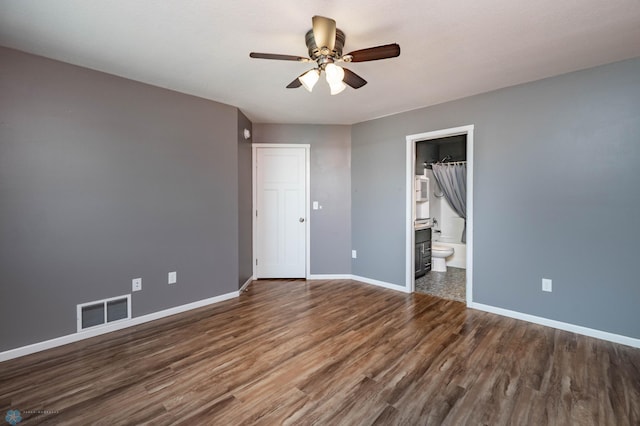 unfurnished bedroom featuring a ceiling fan, wood finished floors, visible vents, baseboards, and ensuite bathroom