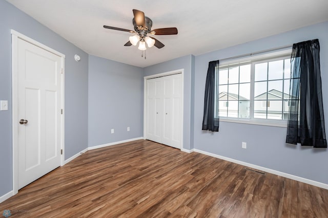 unfurnished bedroom featuring visible vents, ceiling fan, baseboards, wood finished floors, and a closet