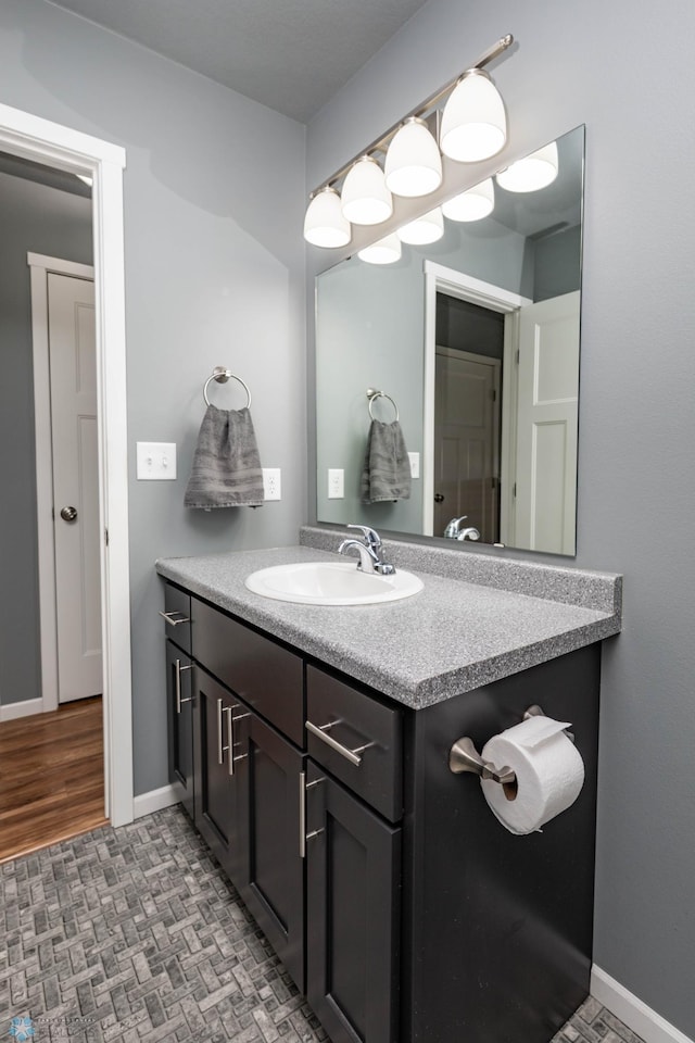 bathroom with vanity, brick floor, and baseboards