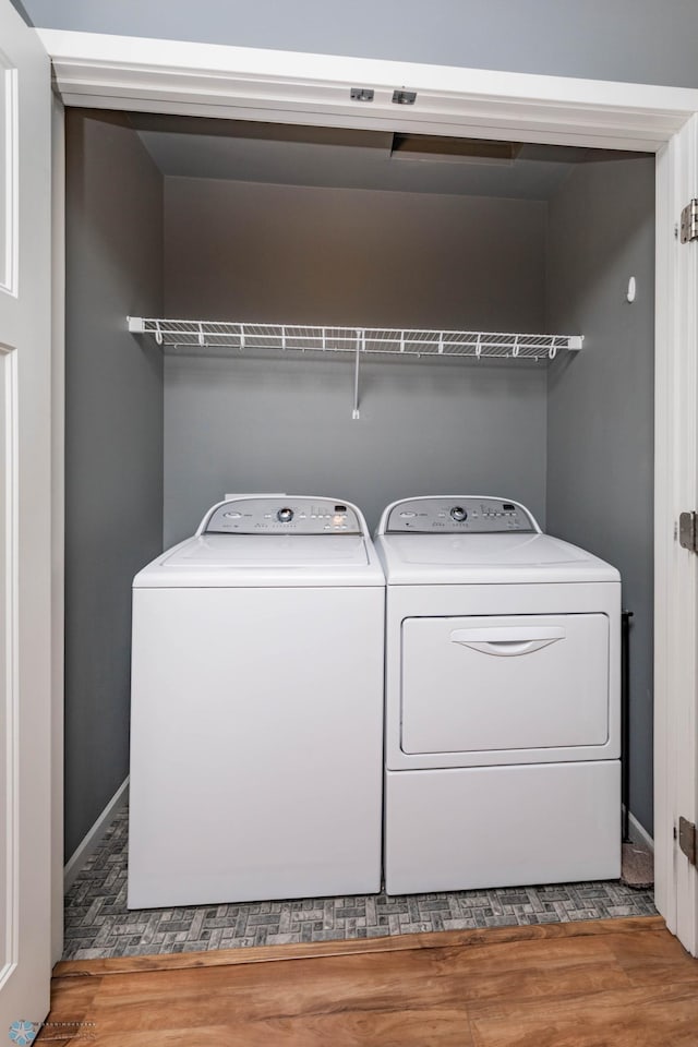 laundry room with baseboards, wood finished floors, laundry area, and washer and clothes dryer