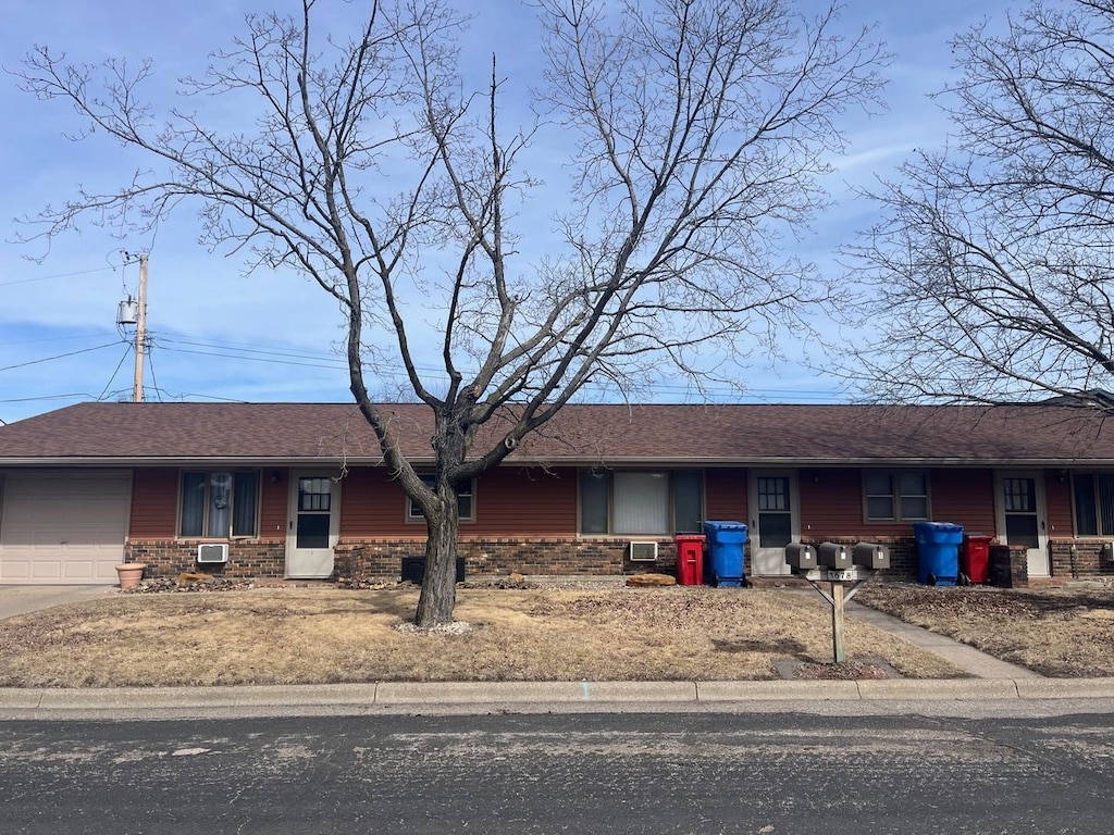 single story home with a garage, brick siding, covered porch, and roof with shingles