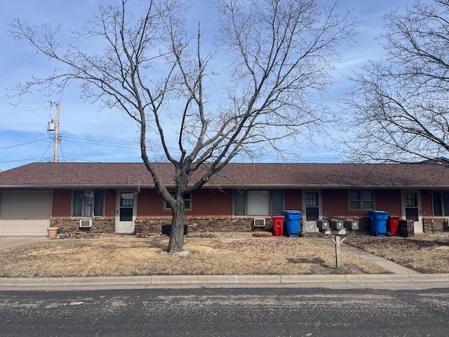 single story home with a garage, brick siding, covered porch, and roof with shingles