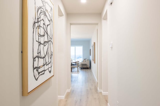 hall featuring baseboards and light wood finished floors