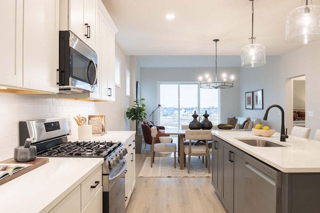 kitchen featuring light wood-style flooring, a sink, light countertops, white cabinets, and appliances with stainless steel finishes