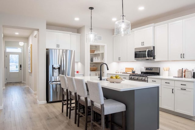 kitchen featuring a kitchen bar, light wood-type flooring, an island with sink, stainless steel appliances, and a sink