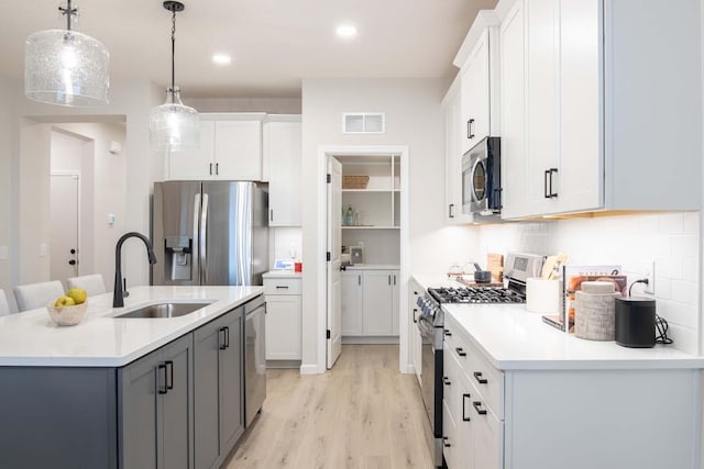 kitchen with visible vents, light wood-style flooring, a sink, stainless steel appliances, and light countertops