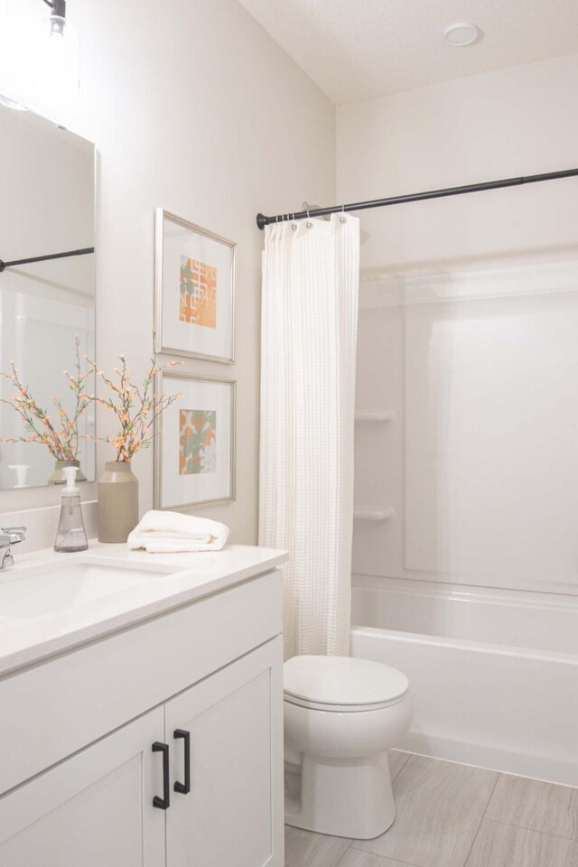 bathroom featuring shower / tub combo, toilet, and vanity