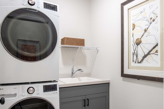 laundry room featuring cabinet space, stacked washer and clothes dryer, and a sink