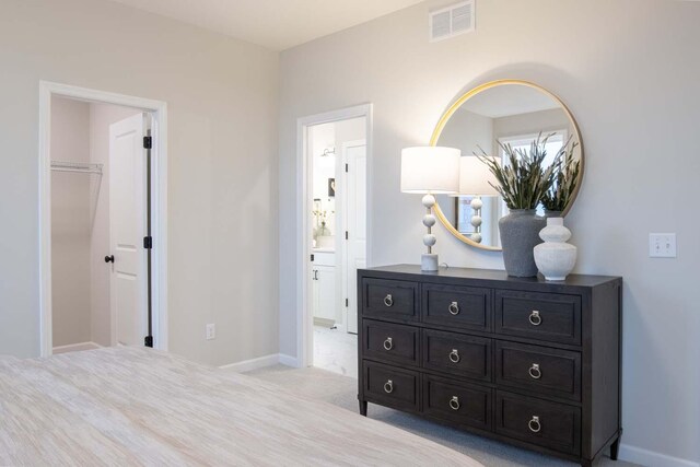 bedroom with carpet flooring, baseboards, visible vents, and ensuite bathroom