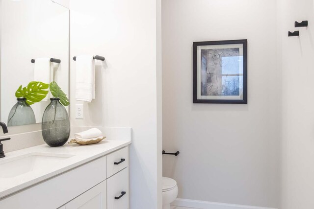 bathroom featuring baseboards, toilet, and vanity