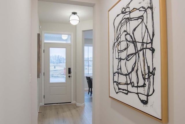 doorway to outside with baseboards and light wood finished floors