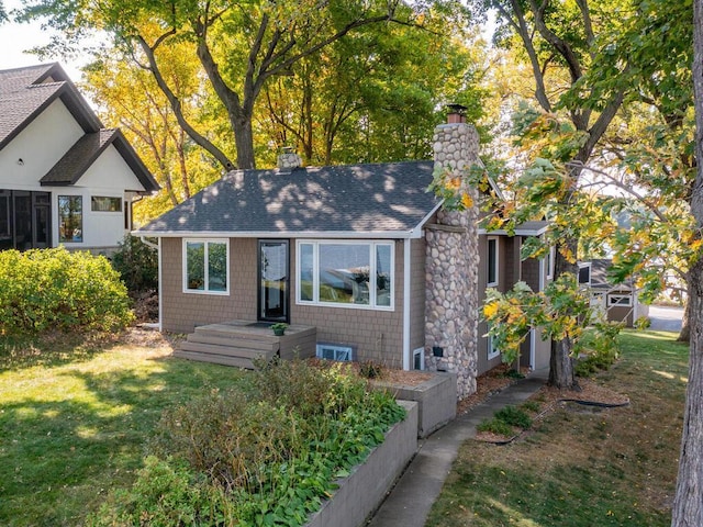 view of front of property with a chimney, a front yard, and a shingled roof