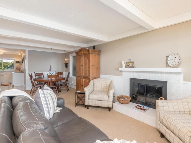 living room with beamed ceiling, carpet, a brick fireplace, and a textured ceiling