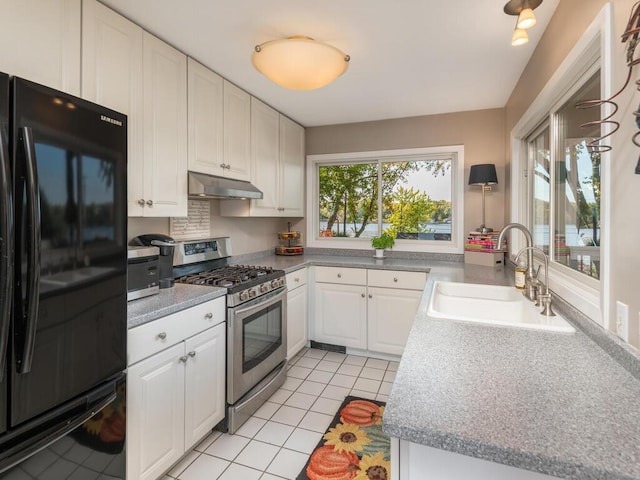 kitchen with stainless steel range with gas cooktop, under cabinet range hood, freestanding refrigerator, plenty of natural light, and a sink